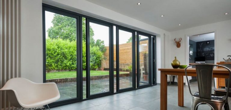 Stylish interior featuring contemporary bi-fold doors offering expansive views of a lush green garden and patio