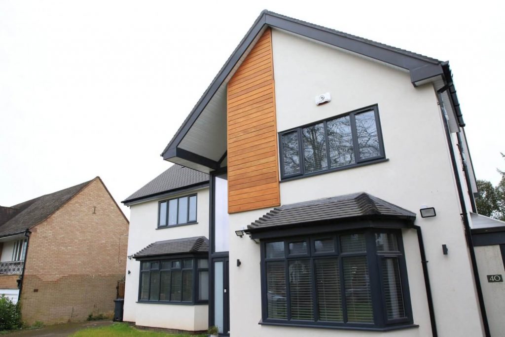 Modern two-storey home with black framed windows, white render finish, and timber cladding detail on the upper facade.
