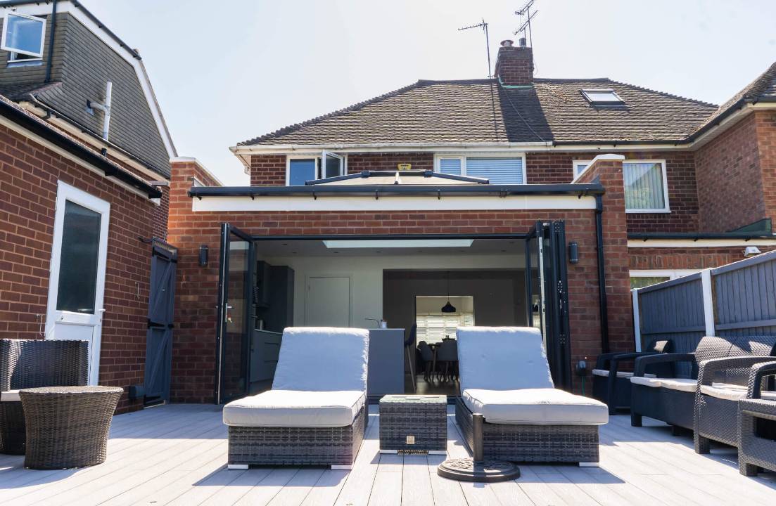 Transform your West Midlands home with a modern extension featuring expansive bi-fold doors, creating seamless indoor-outdoor living perfect for entertaining on a composite deck.