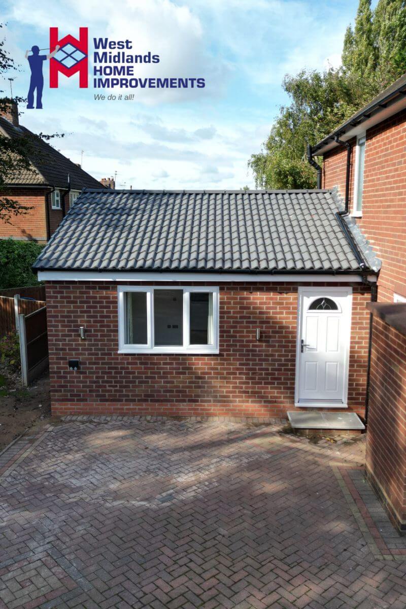 New rear extension with a pitched tiled roof, brickwork to match the main house, and a white uPVC door and window installed by West Midlands Home Improvements.