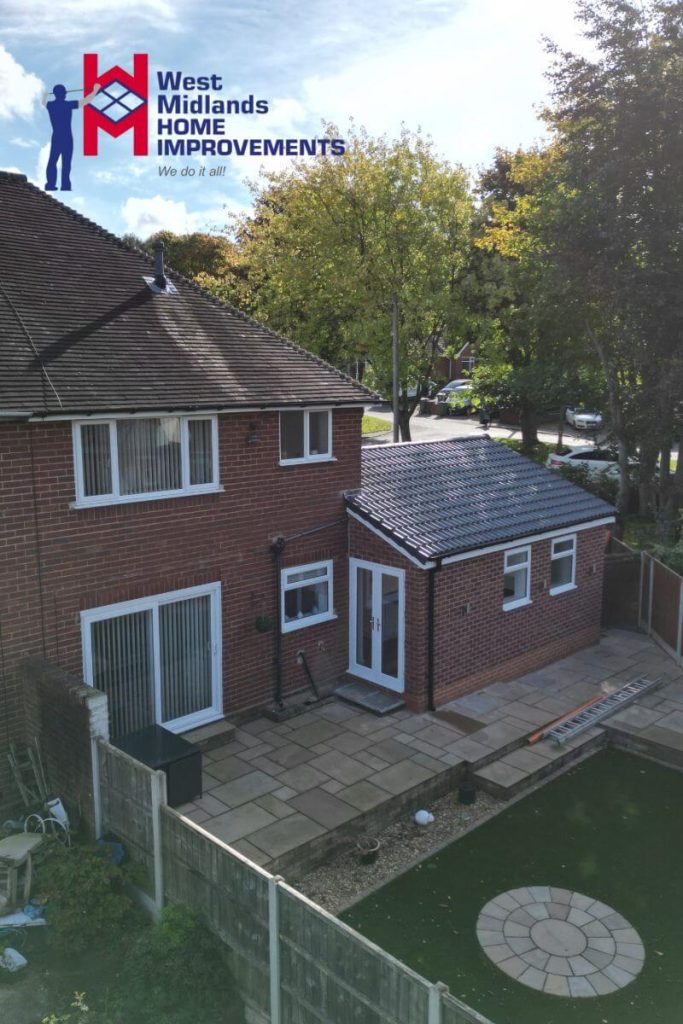Rear house extension with tiled pitched roof, uPVC windows and doors, and a newly paved patio area in a landscaped garden.