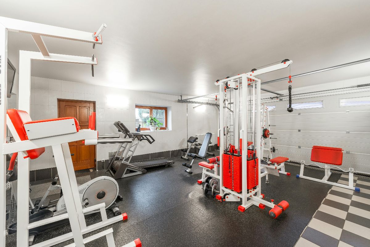 A home garage gym conversion with multiple lifting and cardio machines.