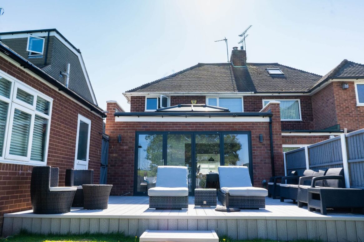 Contemporary rear extension with backyard featuring a composite deck, comfortable outdoor furniture, and a house with bi-fold doors